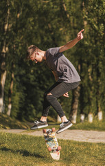 Hipster boy makes a trick with skateboard in the park