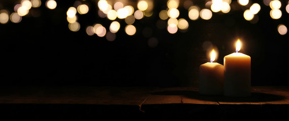 Burning candles over black background with bokeh glitter lights - obrazy, fototapety, plakaty