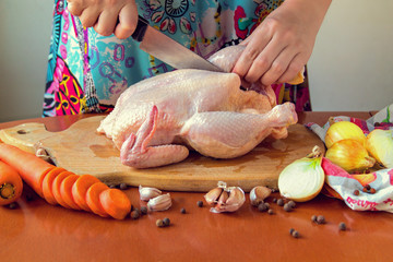 Woman chopping raw chicken for cooking in kitchen