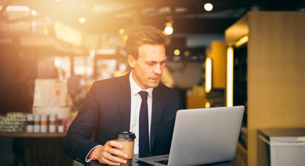 Focused businessman drinking coffee in a cafe working online
