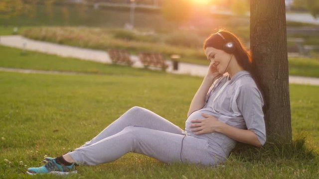 Pregnant Woman listening to music on sunset
