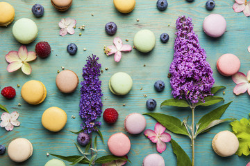 Variety of colorful french sweet dessert - les macarons with flowers and berries.