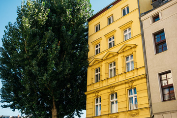 yellow apartment house next to an green tree