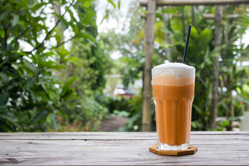 Tea frappe with steam on wooden table in garden