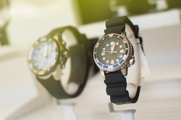 Close up of an beautiful black rubber watch. Beautiful watch in front of other watches. Lens flare in background.