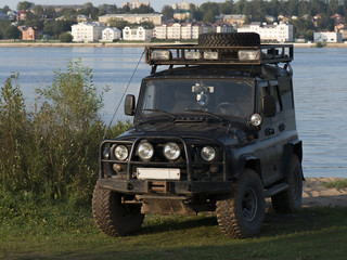 Off-roading car in the background of the river and cityscape