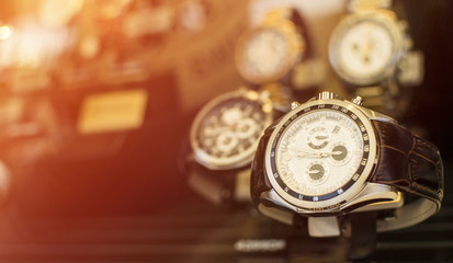 Beautiful brown leather watch in front of other watches. Lens flare in background.