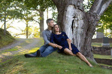 woman leans back against husband under tree