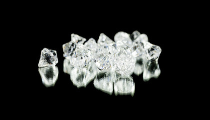 A bunch of shiny diamonds on a black mirror. Medium shot.
