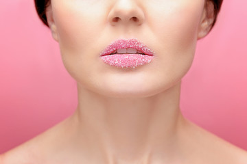 Beautiful young woman with sugary lips on color background