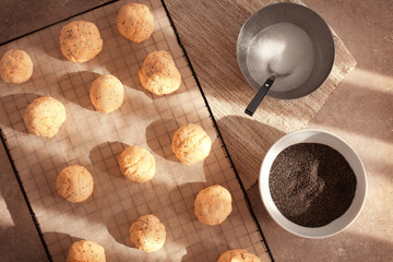 Balls of raw dough with poppy seeds on baking grid