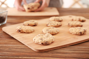 Raw dough with chocolate chips for cookies on wooden board, closeup