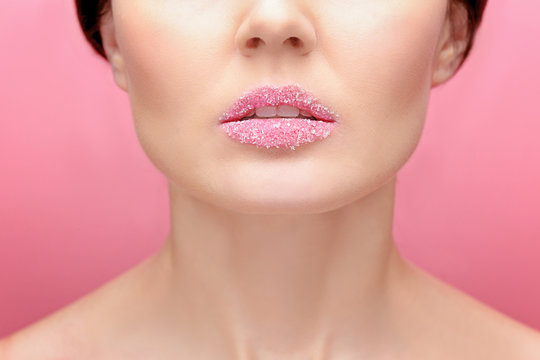 Beautiful young woman with sugary lips on color background