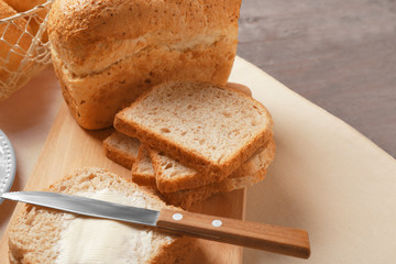 Delicious bread slices with loaf on wooden board