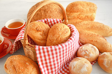Wicker basket and delicious bread on wooden table