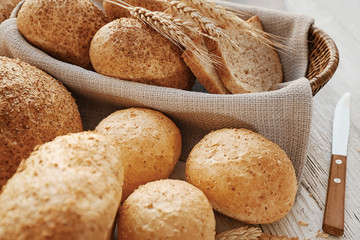 Beautiful composition with wicker basket and delicious bread on wooden table