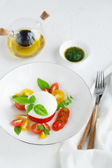 Caprese salad with ripe cherry tomatoes and mozzarella cheese with fresh basil leaves isolated on the white background. Top view.