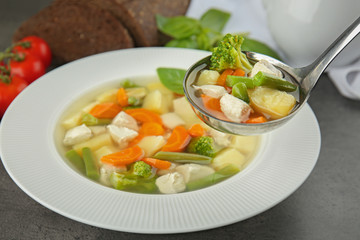 Ladle and plate with delicious turkey soup on table