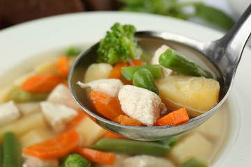 Ladle with turkey soup over plate, closeup