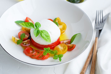 Caprese salad with red and yellow tomatoes, mozarella, basil and olive oil. Close view. White background