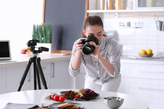 Young woman with professional camera taking still life pictures in kitchen