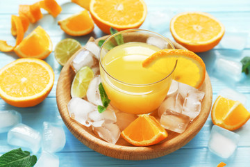 Bowl with glass of orange juice and ingredients on wooden table