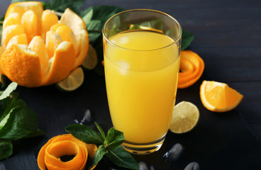 Glass with delicious orange juice and ingredients on slate plate
