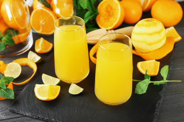 Glasses with delicious orange juice and ingredients on slate plate