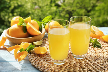 Glasses with delicious orange juice and ingredients on table outdoors