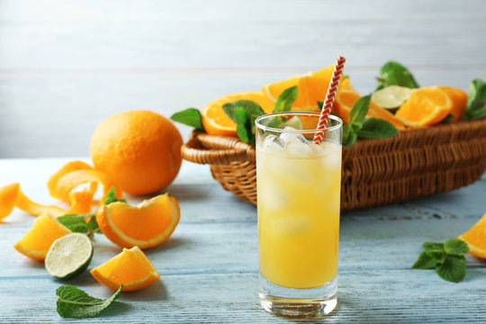 Glass with delicious orange juice and straw on wooden table