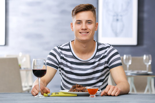 Young man eating delicious ribs in restaurant