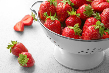 Collander with delicious strawberry on table, closeup
