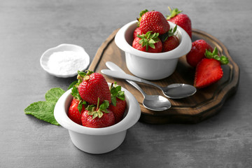 Bowls with delicious strawberry on grey table