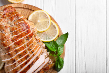 Cutting board with delicious sliced turkey fillet on table