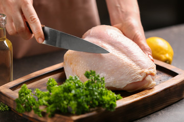 Chef cutting delicious turkey fillet on table