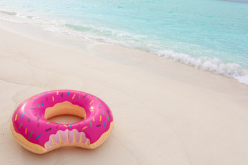 Colorful inflatable donut on sand at sea coast