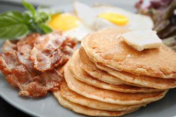 Tasty breakfast with fried eggs, pancakes and bacon on plate