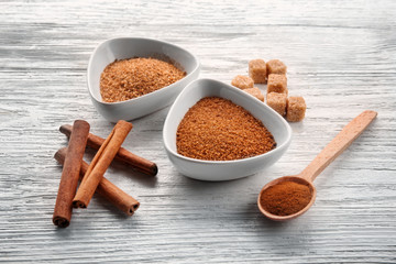 White bowls with cinnamon sugar and sticks on wooden background