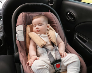 Adorable baby sleeping in child safety seat inside of car