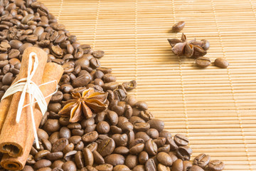 Coffee bean, cinnamon,star anise and nutmeg in the background bamboo Mat. Roasted coffee bean background close up.