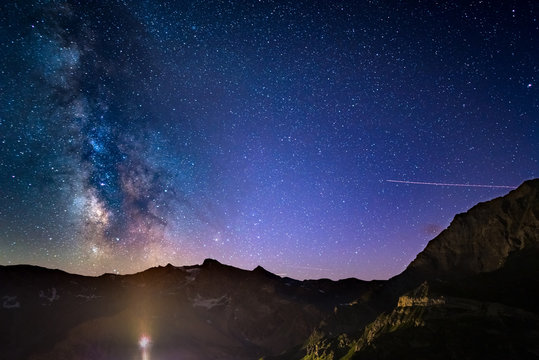The colorful glowing Milky Way arch and the starry sky from high up on the Alps.