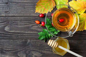 rose hip tea with honey in transparent cup with autumn leaves