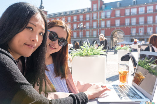 Asian women with a laptop sitting outside a cafe In Madrid