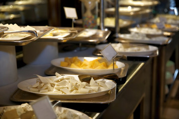 Plates with different kinds of cheese on table at buffet