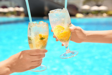 Young women with glasses of lemonade near swimming pool
