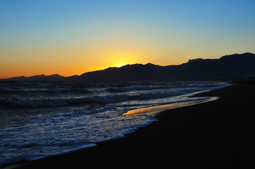Fototapeta premium Beautiful sunset on the beach with mountains in the background