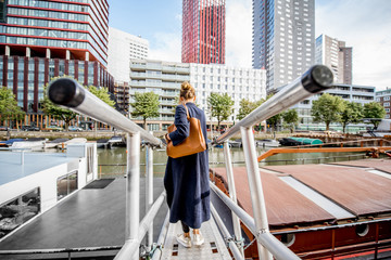 Woman walking back on the bridge at the modern district with slyscrapers in Rotterdam city
