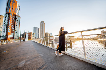 Woman enjoying modern cityscape view standing on the bridge during the morning in Roterdam city - obrazy, fototapety, plakaty