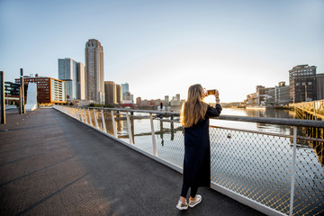Woman enjoying modern cityscape view standing on the bridge during the morning in Roterdam city