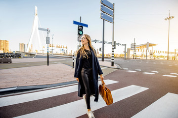 Stylish businesswoman crossing the street at the modern district during the morning in Rotterdam...